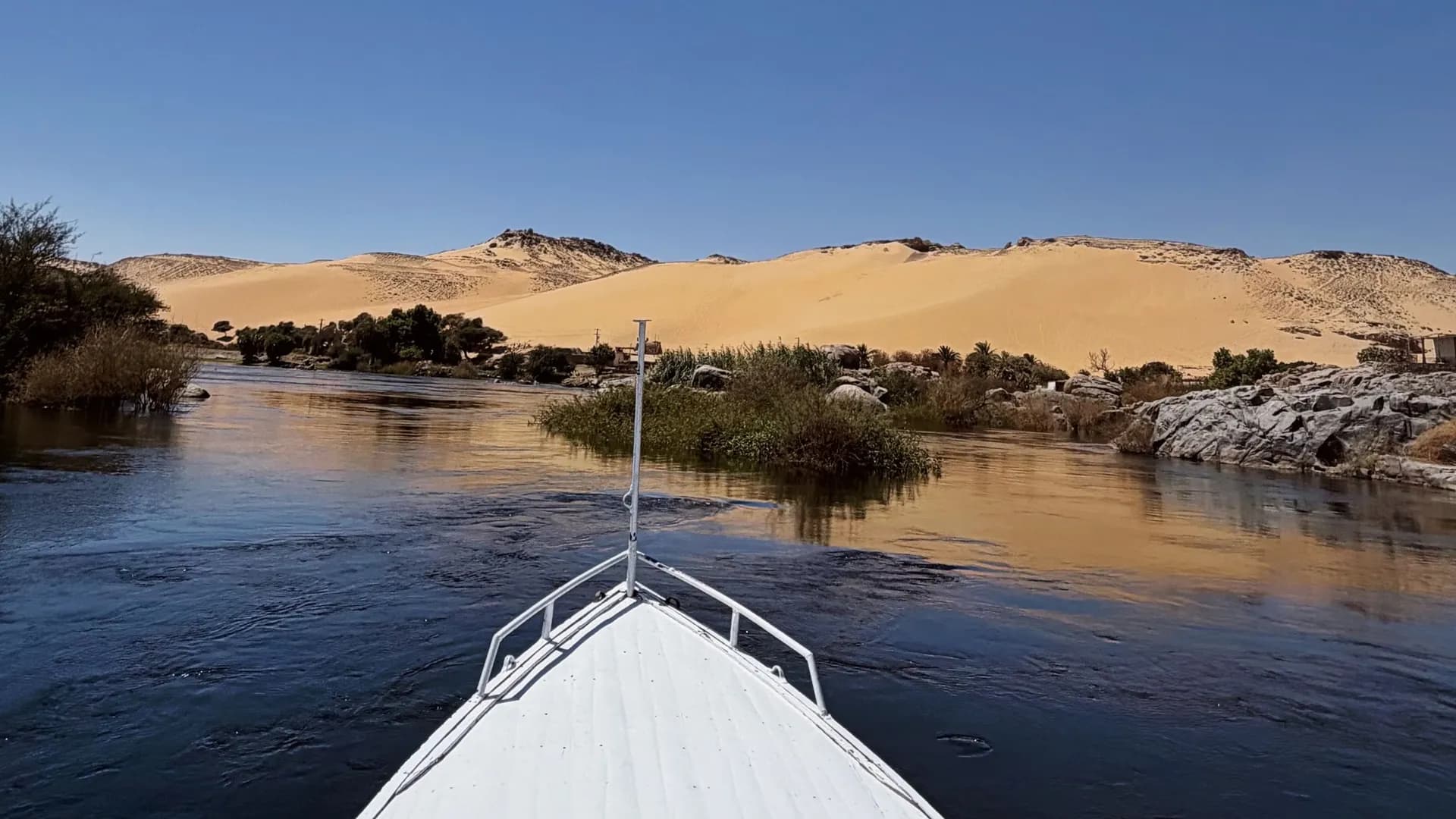 La proue d'un bateau sur le Nil, face aux dunes d'Assouan