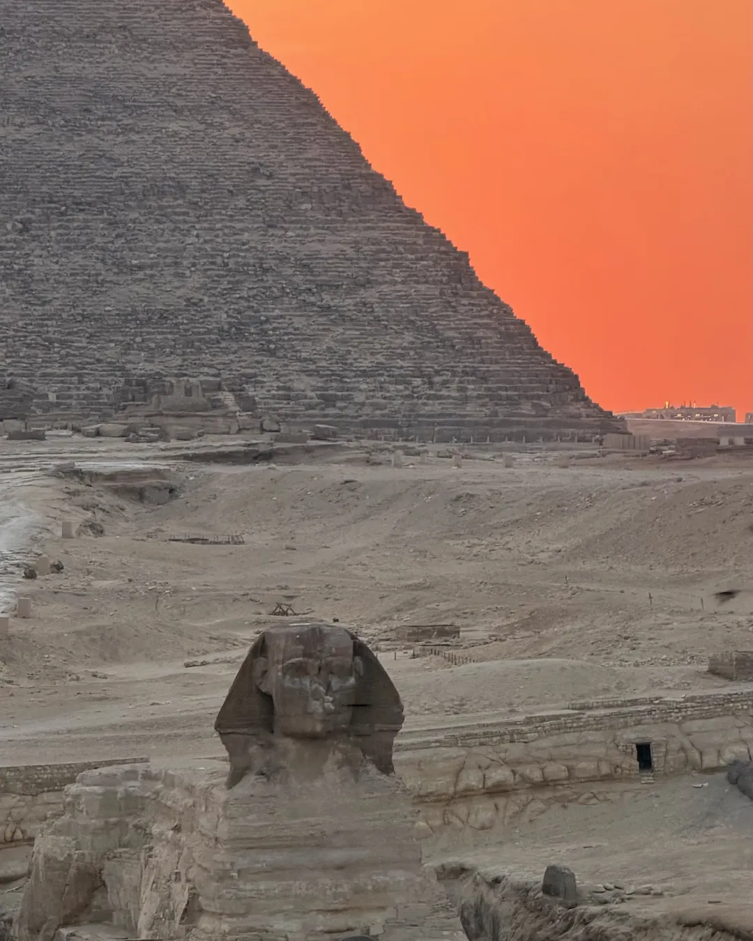 Le Sphinx et une pyramide de Gizeh sous un ciel orangé