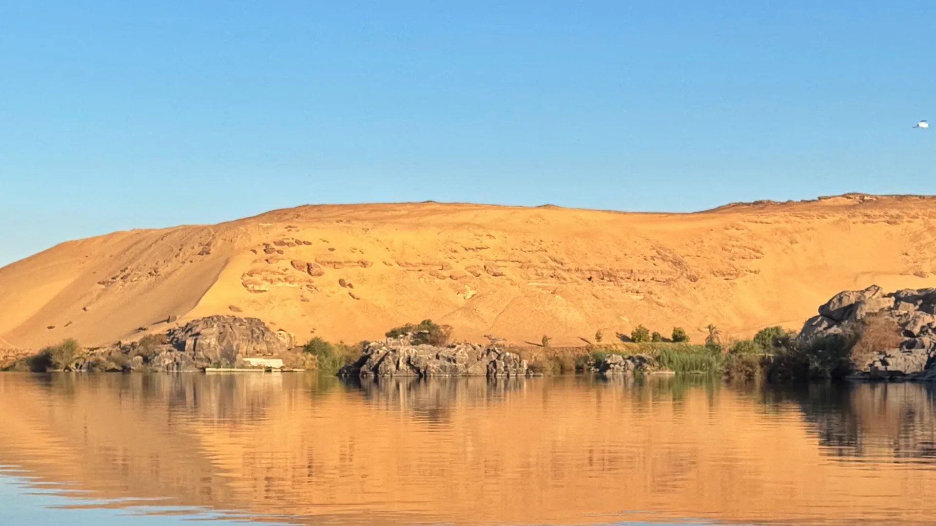 Une dune dorée de la rive ouest d'Assouan, reflétée dans le Nil